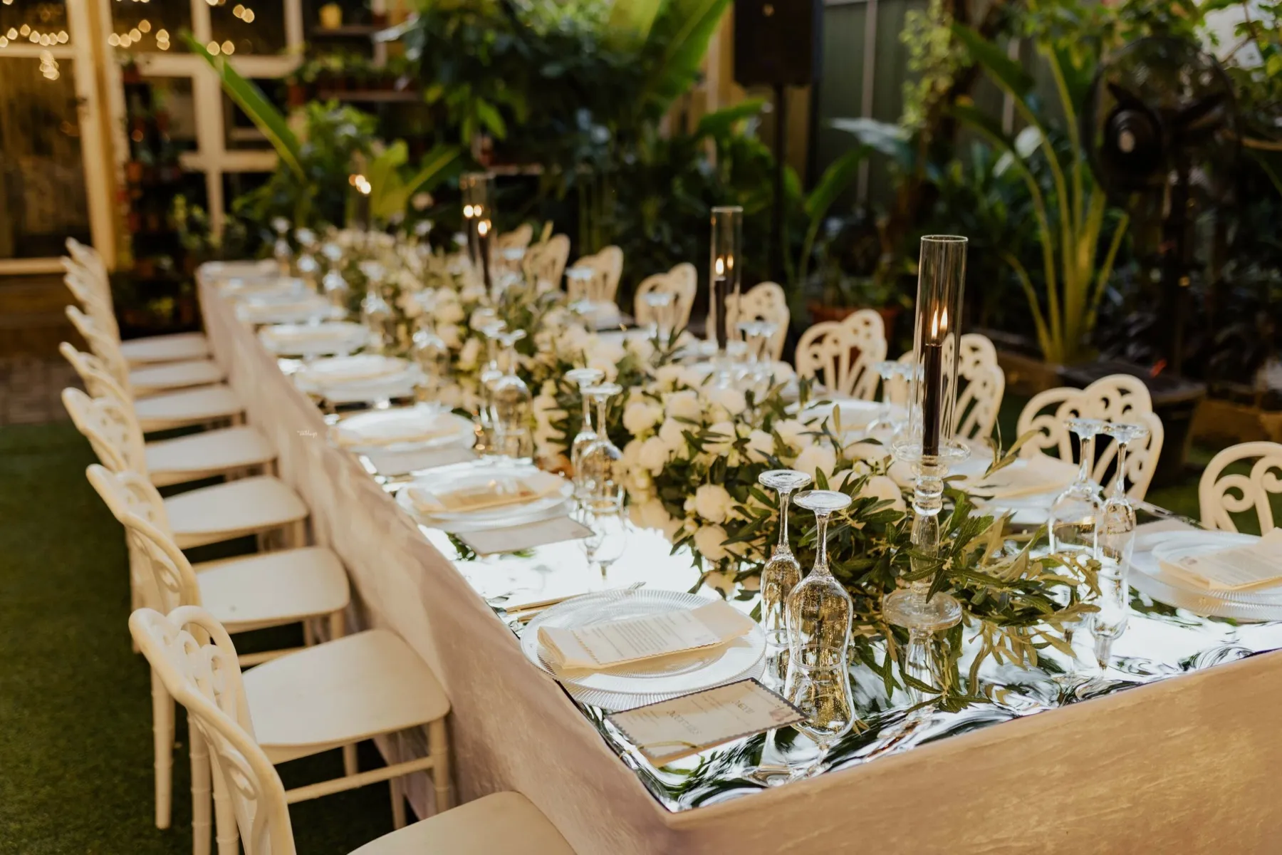 Long garden tables set in white with greenery runners