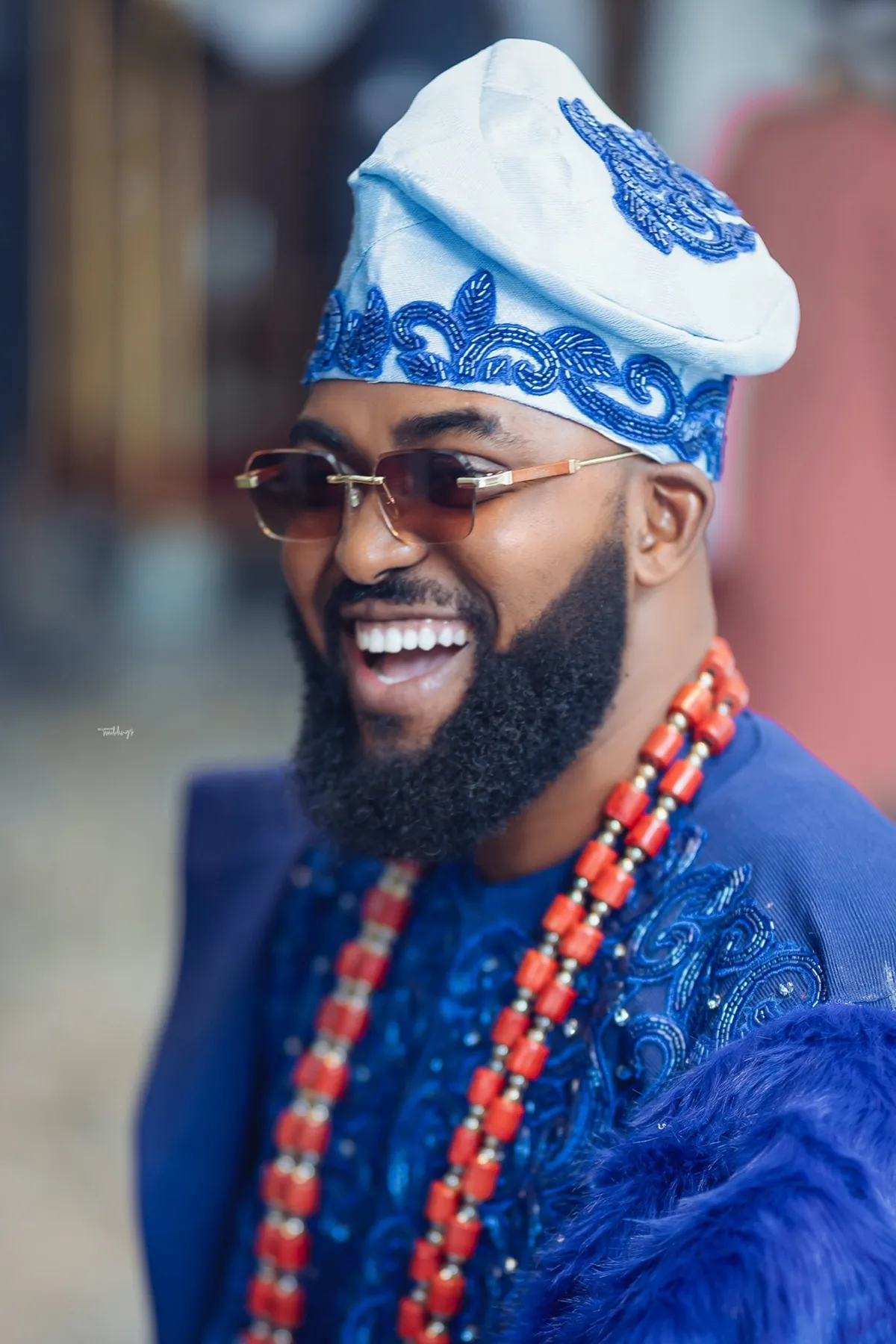 Neon laughing in a blue agbada and coral beads